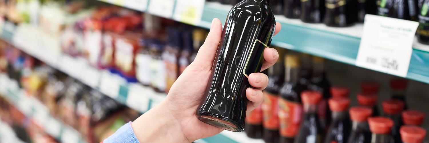 A person is holding a bottle of soy sauce in a store. A person is holding a bottle of soy sauce in a store.