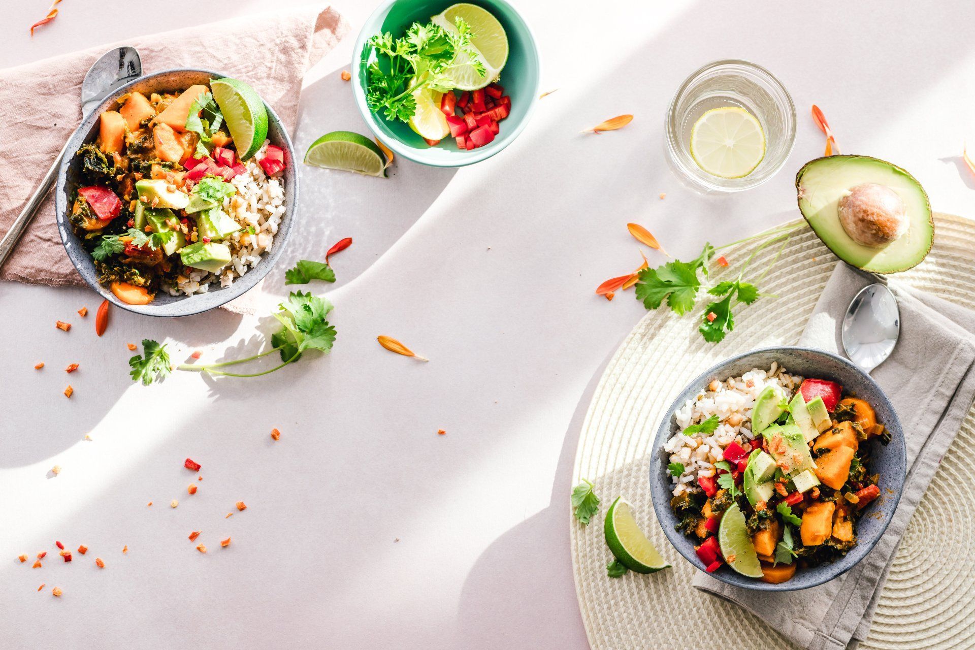 A table topped with bowls of food and a glass of water. A table topped with bowls of food and a glass of water.