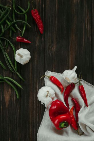 Red peppers , garlic and green beans on a wooden table.