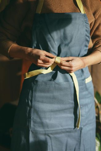 A woman wearing a blue apron with a yellow ribbon around her waist