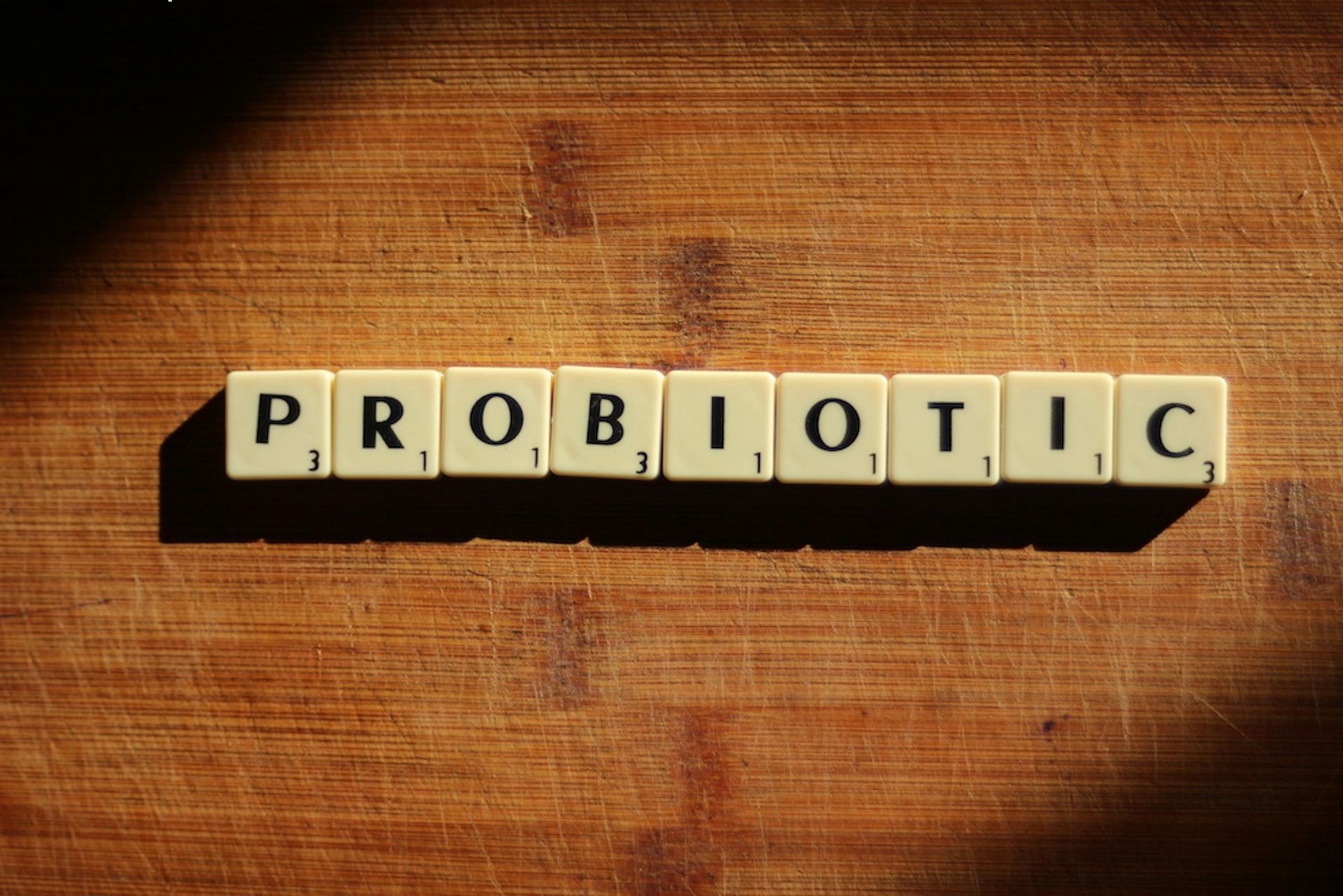 The word probiotic is written in scrabble tiles on a wooden table. The word probiotic is written in scrabble tiles on a wooden table.