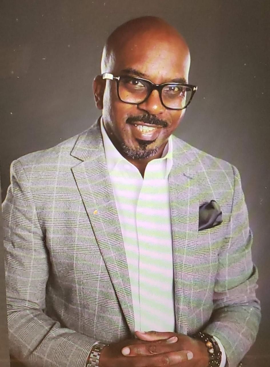 A man wearing a suit and glasses is smiling for the camera.