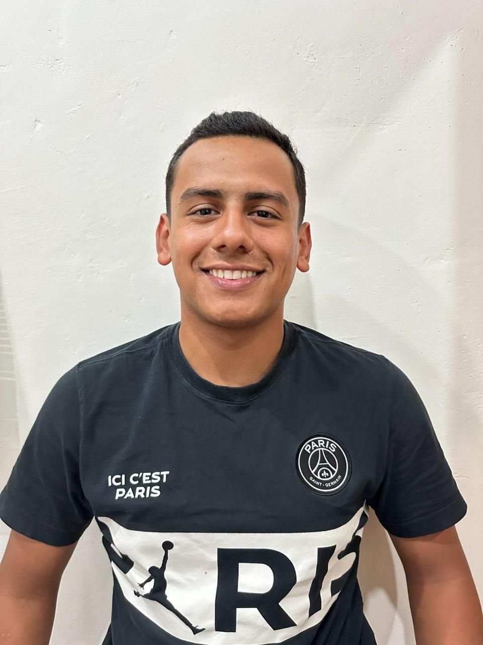 A man wearing a black shirt with the letter r on it