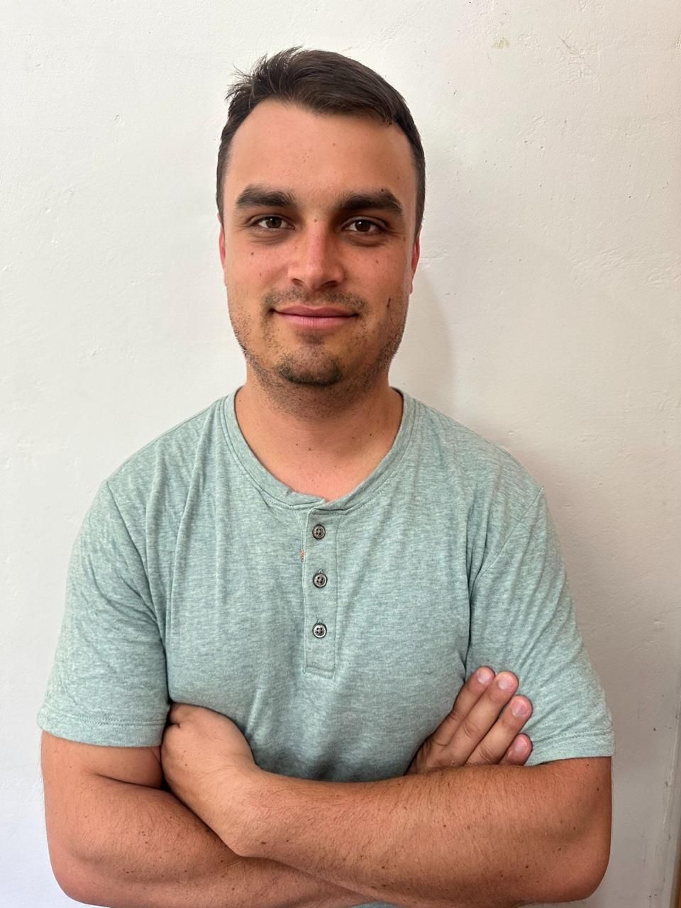 A man in a green shirt is standing with his arms crossed.
