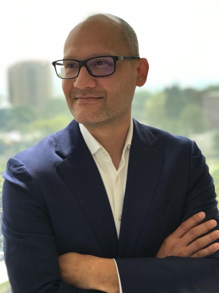 A man wearing a suit and glasses is smiling for the camera.