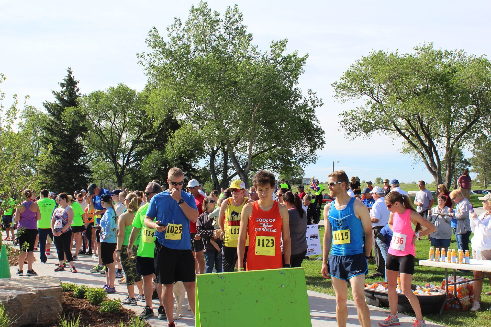 Runners line up at the starting line of an outdoor race on a sunny day.