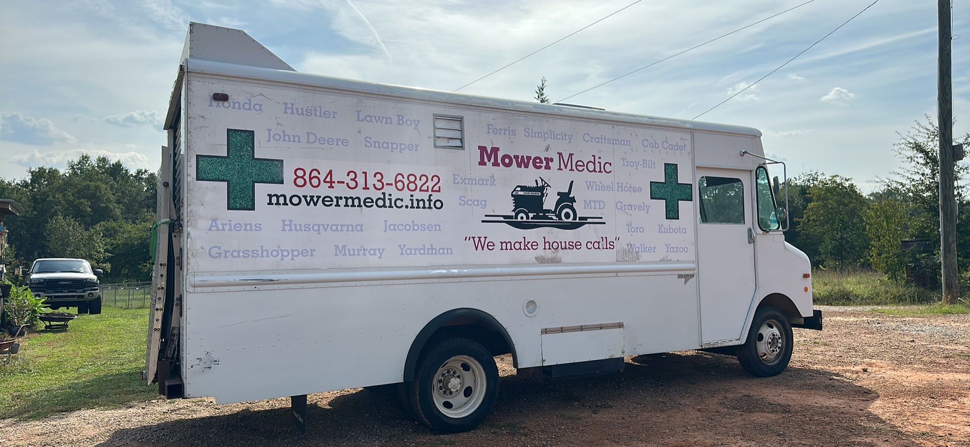 White mobile pet grooming van with “Mower No” branding parked on gravel under a cloudy sky