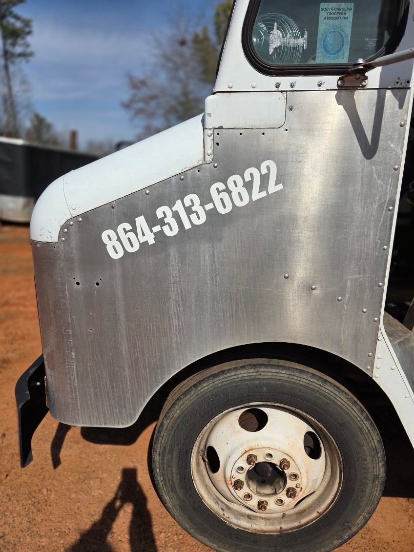 White utility truck side panel with phone number 864-315-6822 and a dirty front wheel