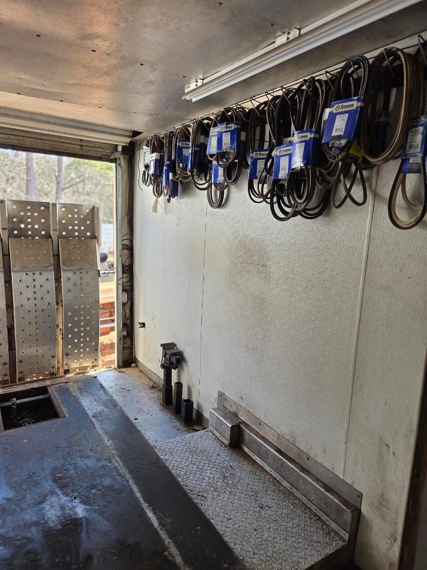 Empty cargo trailer interior with mounted blue power tools and coiled cords along the wall