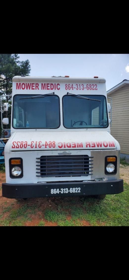 White medical transport van parked on grass, front view with service signage and license plate visible