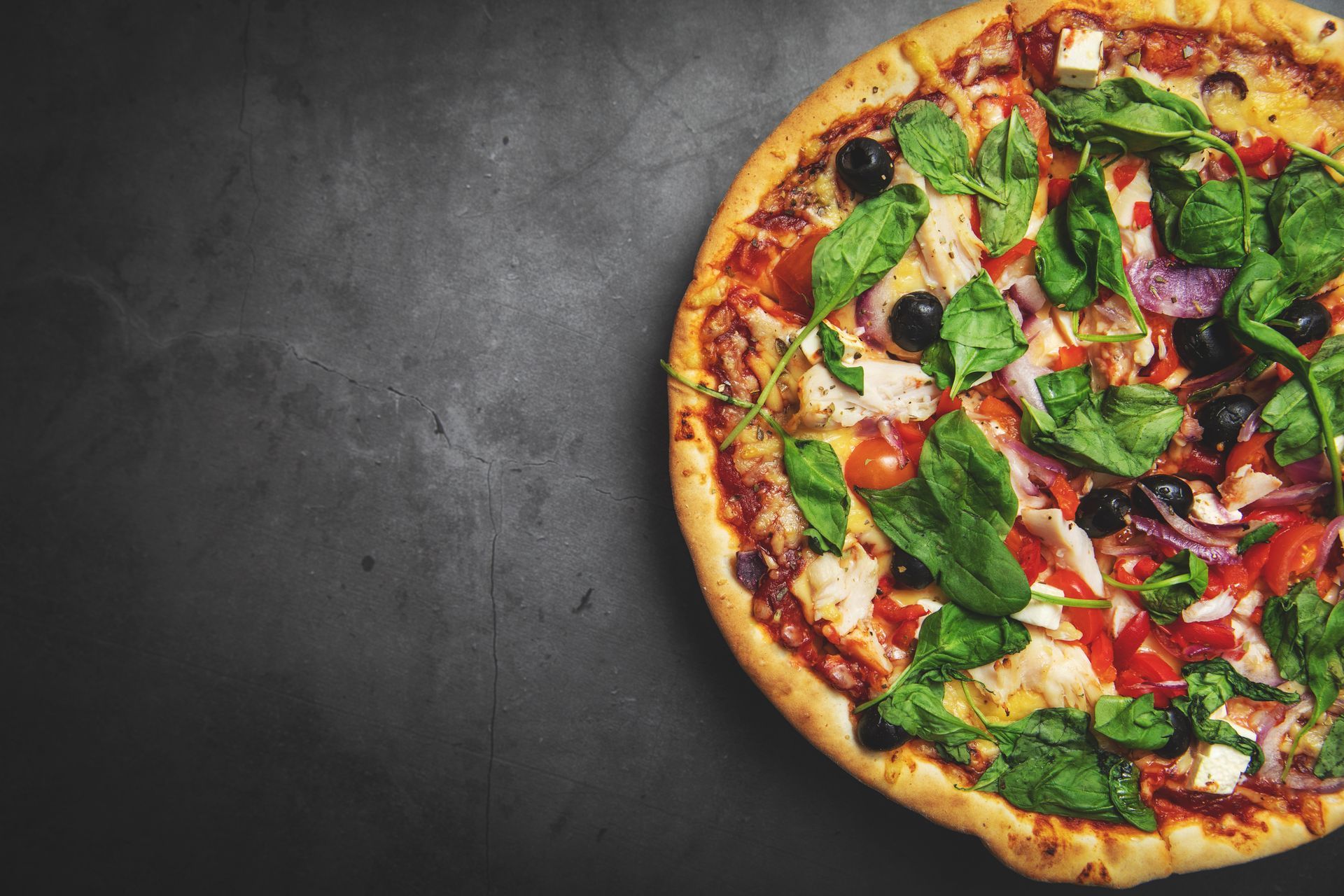 greek chicken pizza on black stone background with copy space.