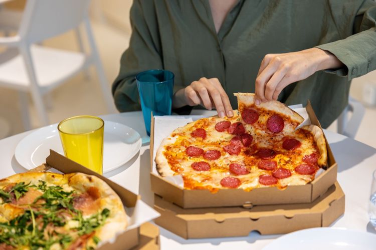 Person Grabbing Slice Of Pepperoni Pizza
