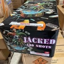 Box of fireworks labeled “JACKED 130 SHOTS” sitting on stacked cartons.