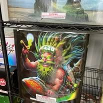 Colorful fantasy creature poster with glowing green face and wild hair on a store shelf