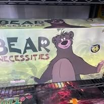 Bear Necessities promo sign with a smiling cartoon bear on a light green background, in a store display.