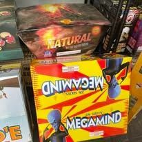 Stacked fireworks boxes, including colorful Megamind and Natural packages on a store shelf.