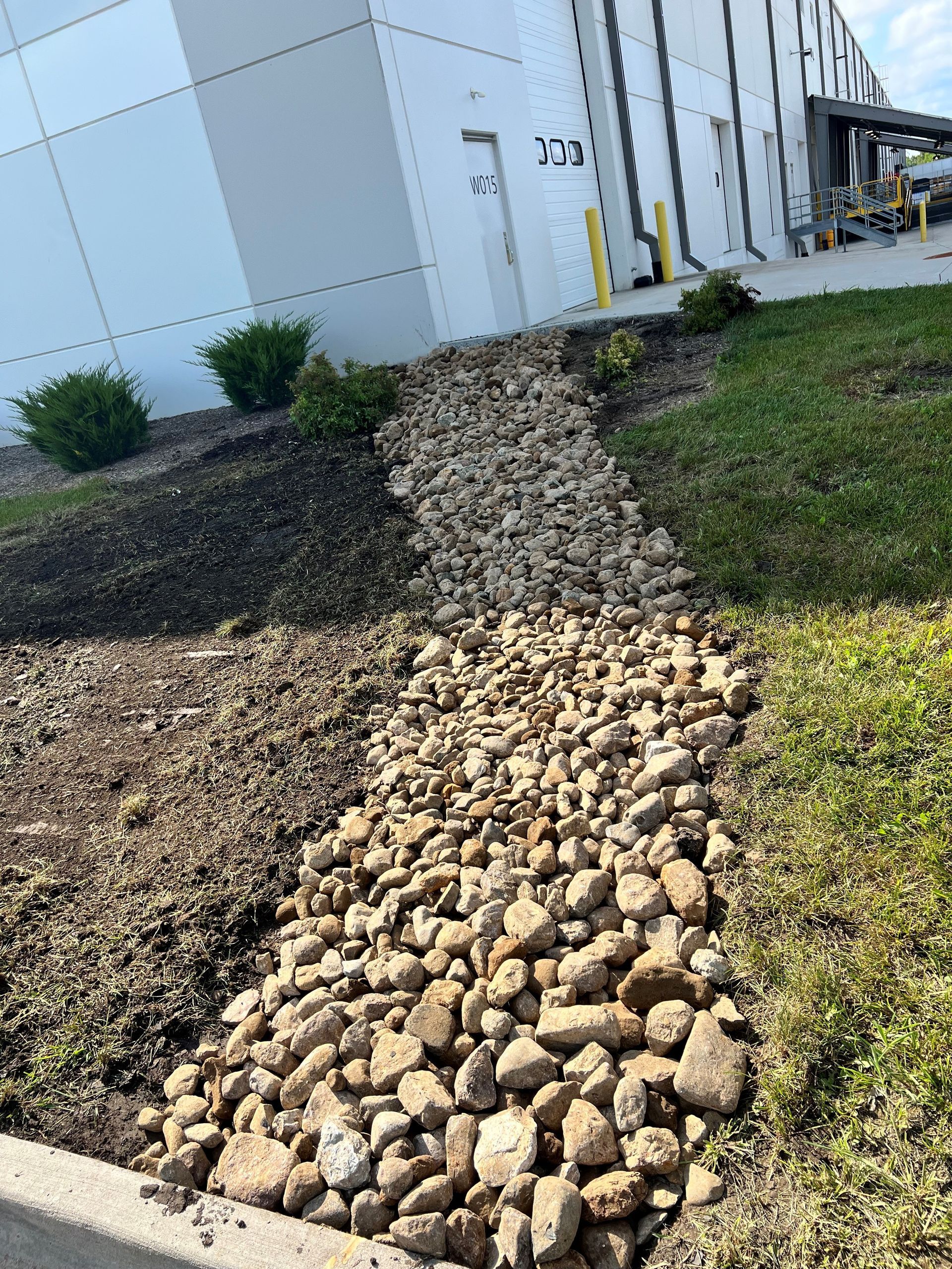 Erosion control rock bed installed for water runoff management on a Central Iowa commercial property by CD’s Lawn Care
