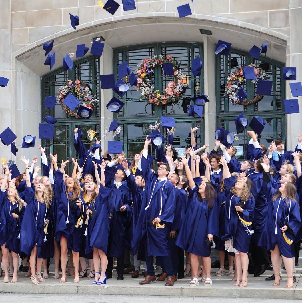 A large group of graduates are throwing their caps in the air