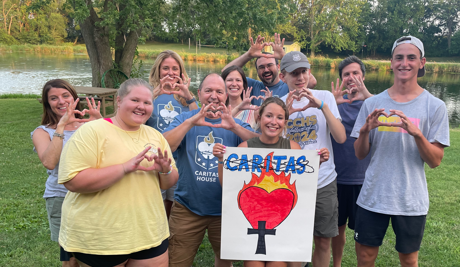 A group of people are posing for a picture while holding a sign that says caritas.