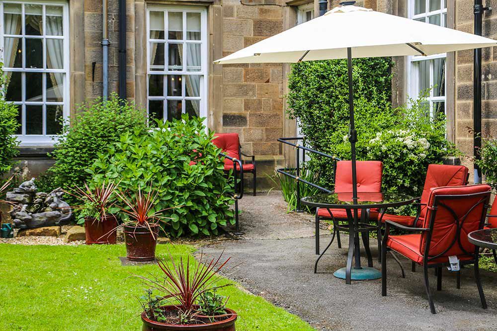 Outdoor garden seating area at Nunthorpe Hall with parasols and planting