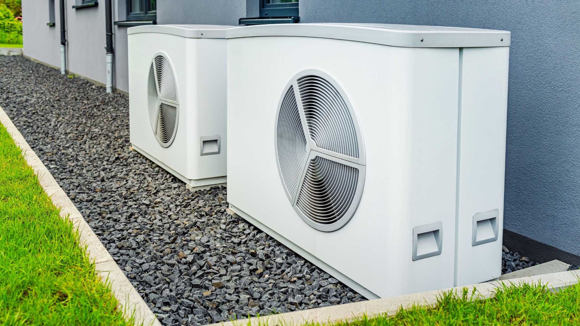 Two white air conditioners are sitting on the side of a building.