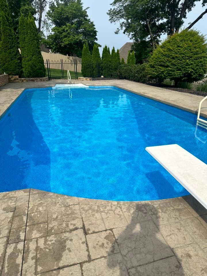 A large blue swimming pool with a diving board in the middle
