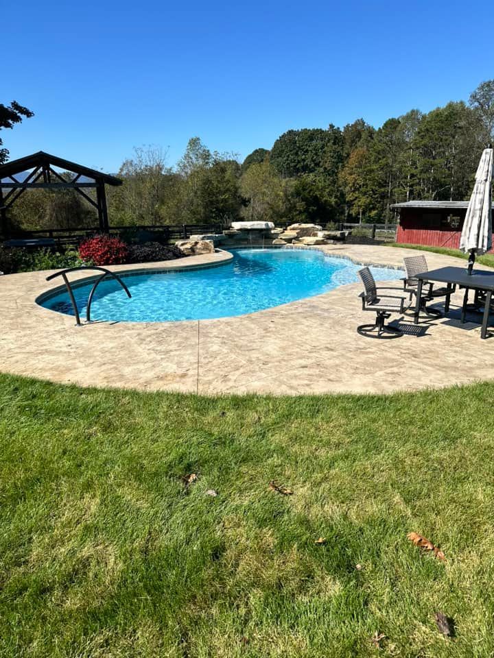 There is a large swimming pool in the middle of a lush green field.