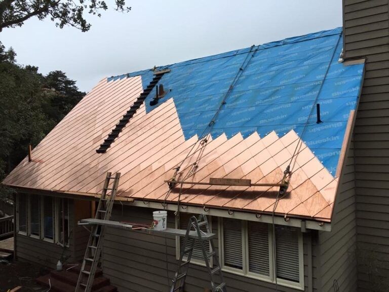 Copper roof installation in progress on a house; part covered with blue underlayment, part with copper sheets.