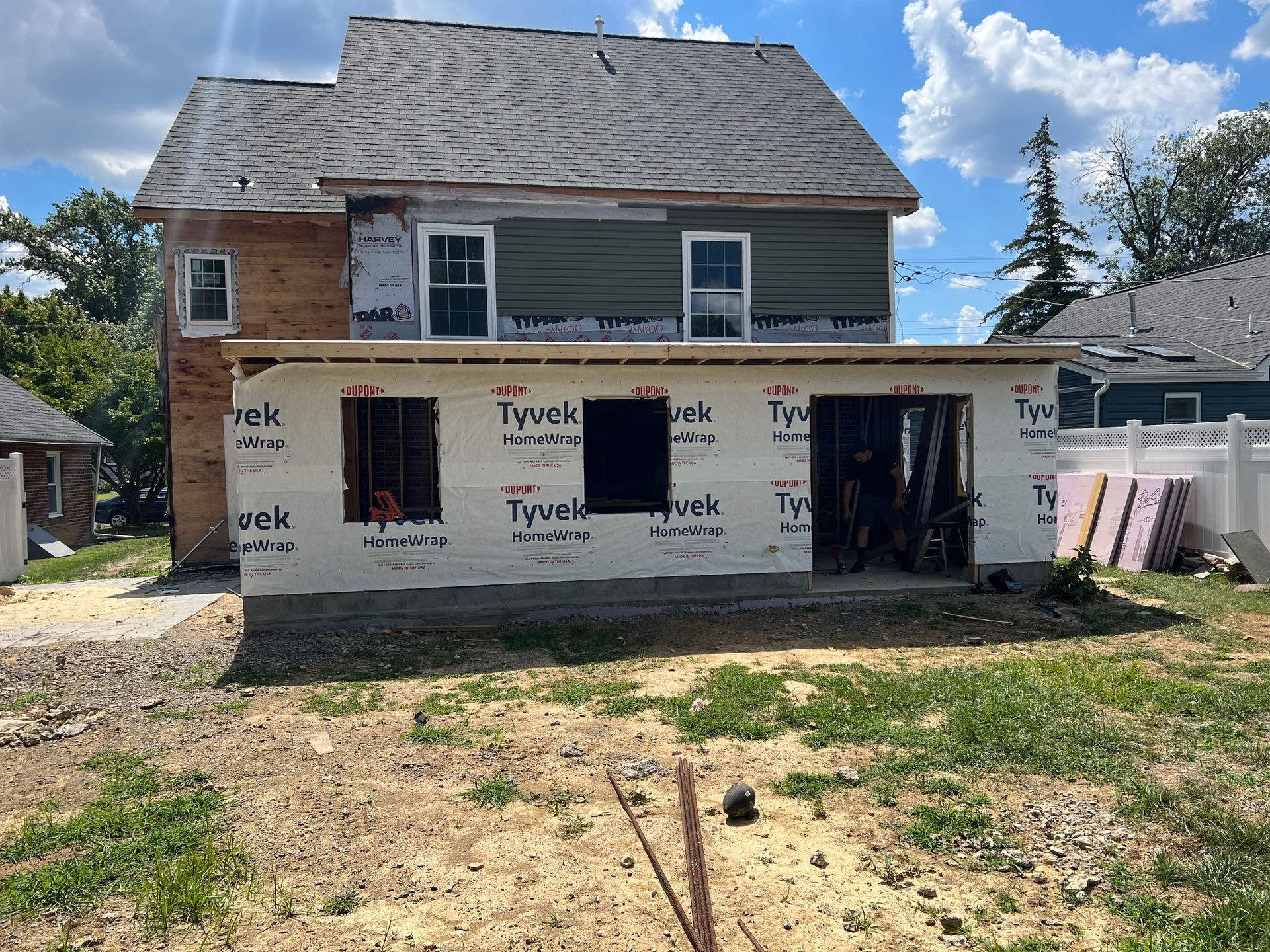 House under construction, with new addition. Tyvek wrap covers the addition, siding partially installed.