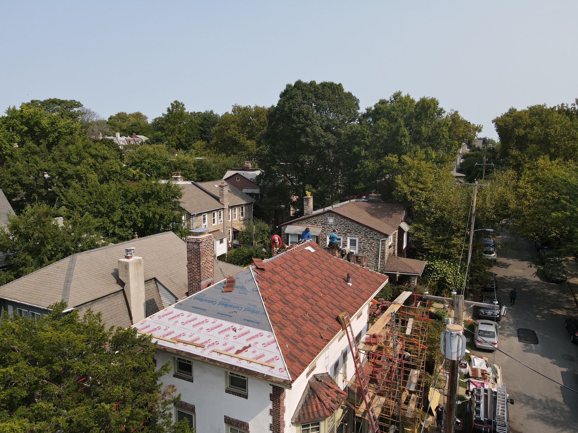 Aerial view of residential neighborhood with houses and trees under a clear sky.