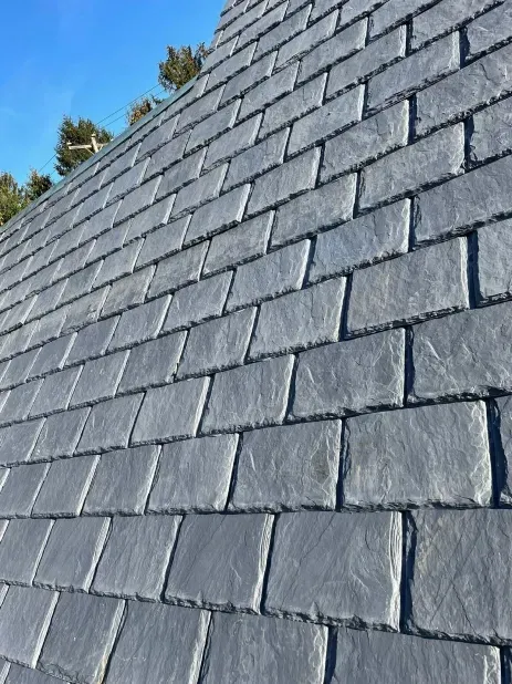 Close-up of a gray slate roof against a clear blue sky.
