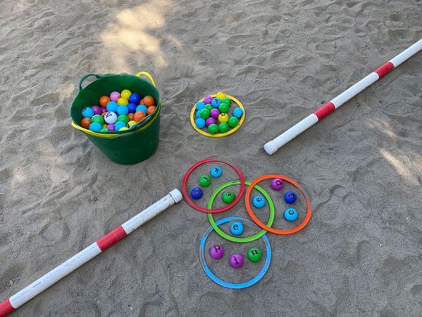 Colorful plastic balls in buckets and rings on sand for an outdoor game