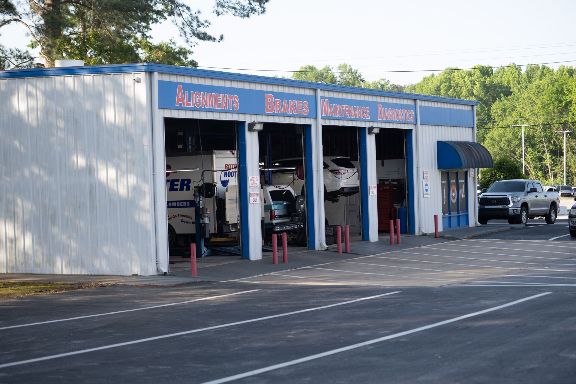 Auto repair shop with three bays, cars on lifts, and a small waiting area.