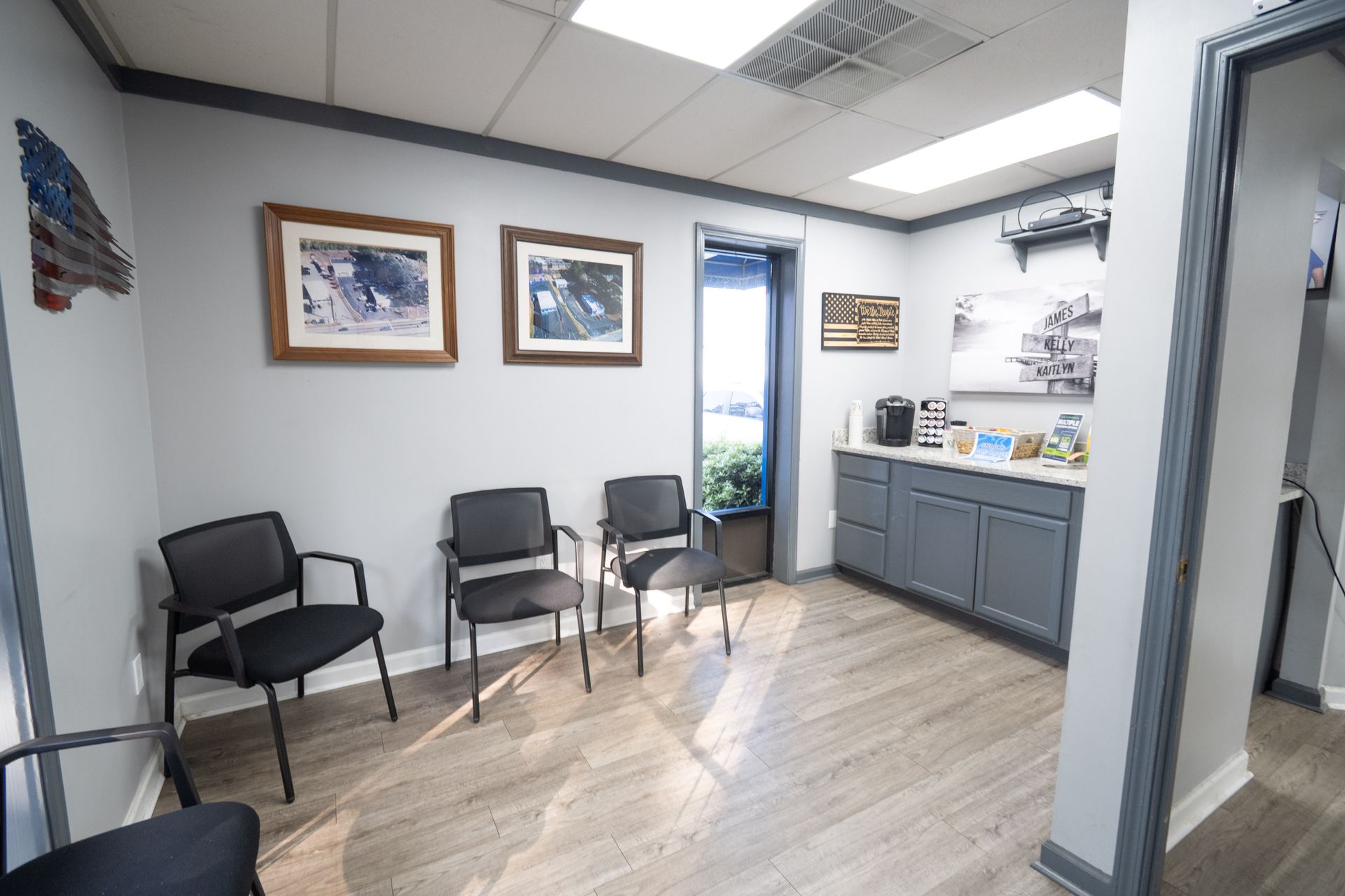 Waiting room with gray walls, wood-look floor, chairs, and framed artwork.