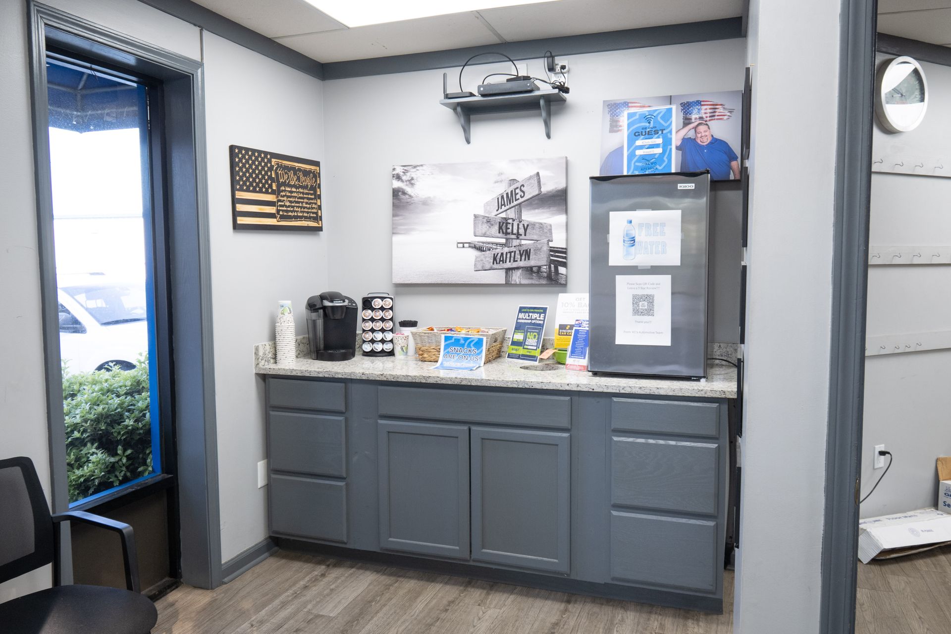 Office break room with gray cabinets, coffee maker, snacks, and a mini-fridge.