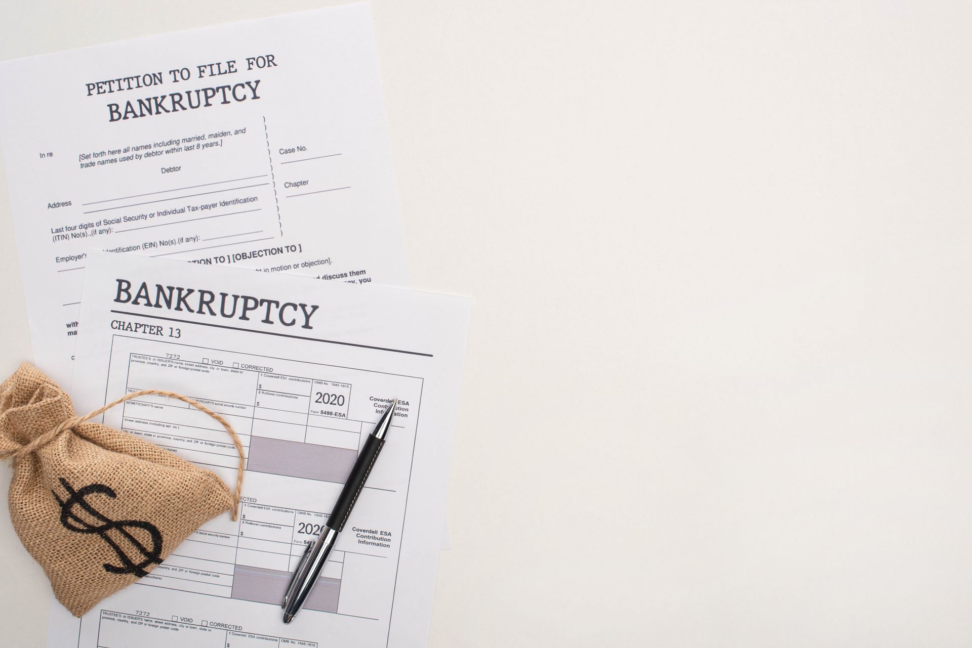 Bankruptcy forms and money bag with a pen on a white surface.