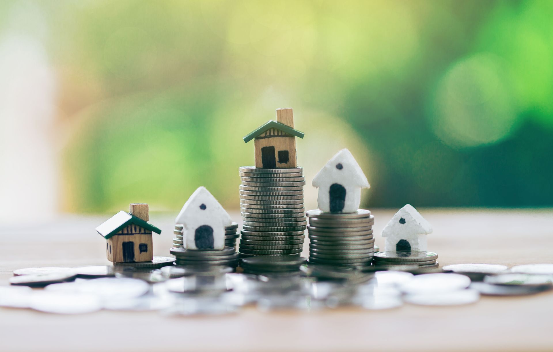Miniature houses atop stacks of coins; real estate investment concept.