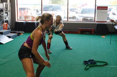 Two women exercising with resistance bands in a gym near large windows in Urbandale, IA