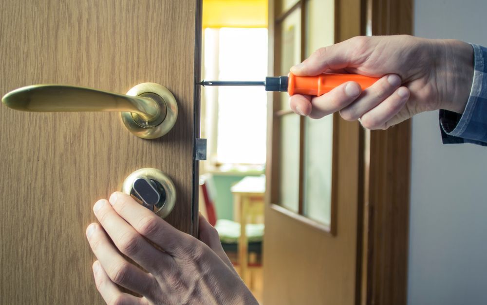 Person Using a Screwdriver to Install or Repair a Door Lock on a Wooden Door — Yamba Locksmiths in Clarence Valley, NSW