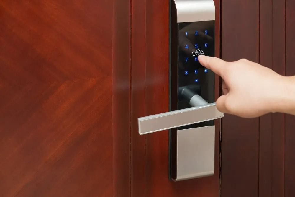 Hand Entering Pin on a Digital Door Lock With a Silver Handle on a Brown Door — Yamba Locksmiths in Maclean, NSW
