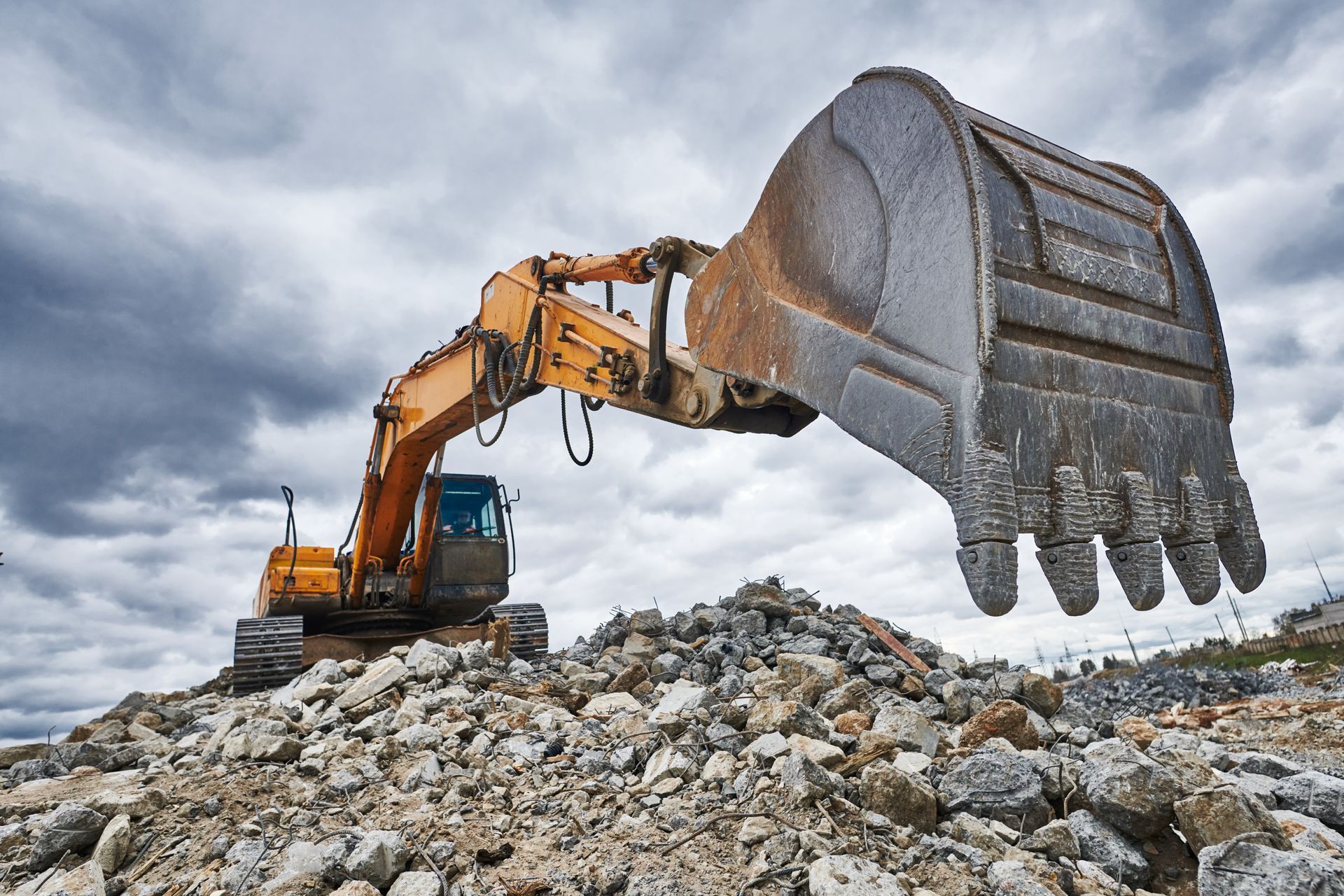 A yellow excavator is digging in a pile of rocks.