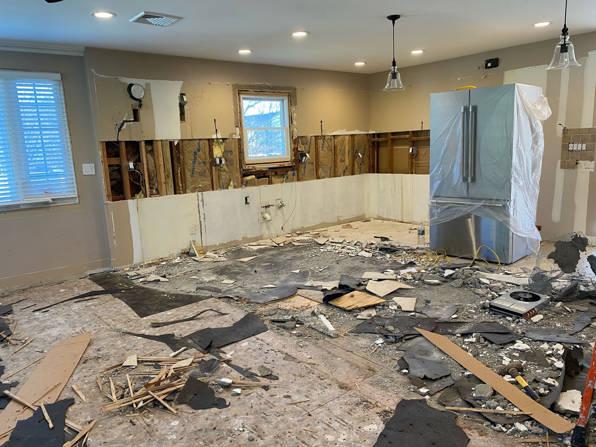 A kitchen is being remodeled with a refrigerator in the middle of the room.