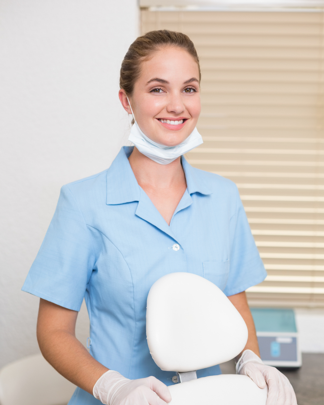 Two medical staff in a clinic, one in blue scrubs smiling and talking with a colleague.