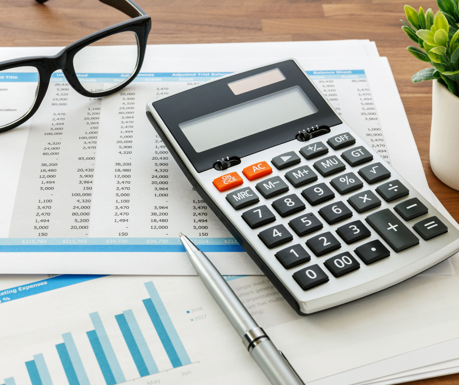 Calculator, glasses, pen, and financial charts on a desk