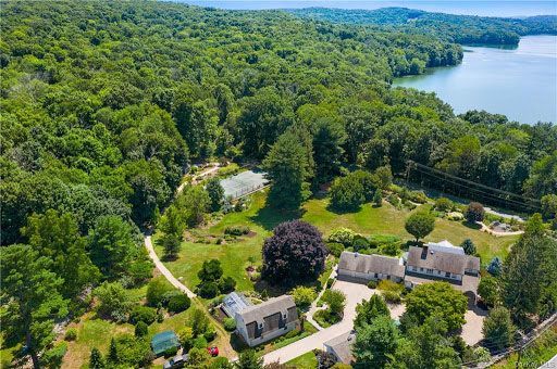 Aerial view of lakeside homes surrounded by dense green forest and winding paths
