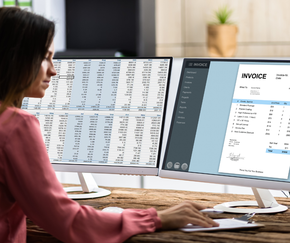 Person working at a desk with dual monitors showing spreadsheets and an invoice on screen