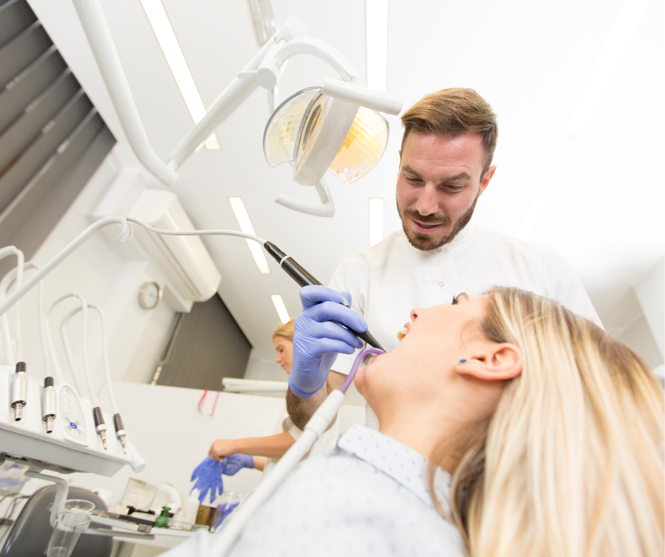 Dentist examining a patient’s mouth with dental tools in a bright clinic
