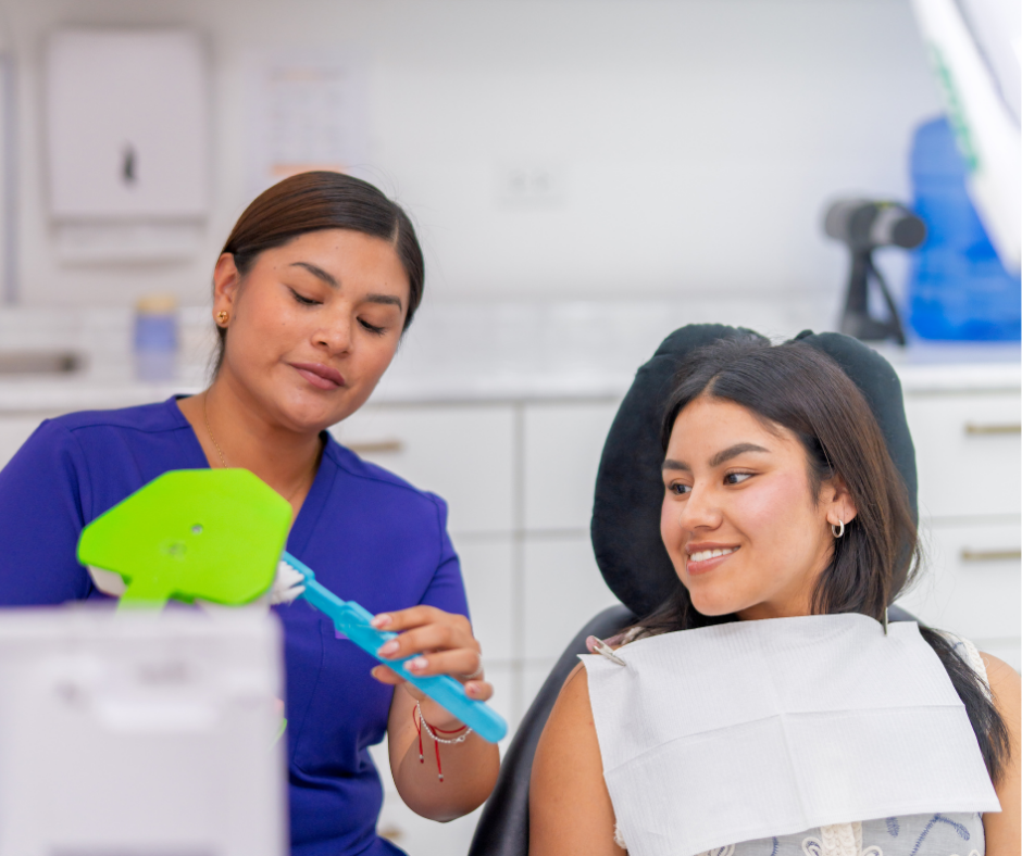 Dentist showing a child a green dental model during a checkup in a bright clinic