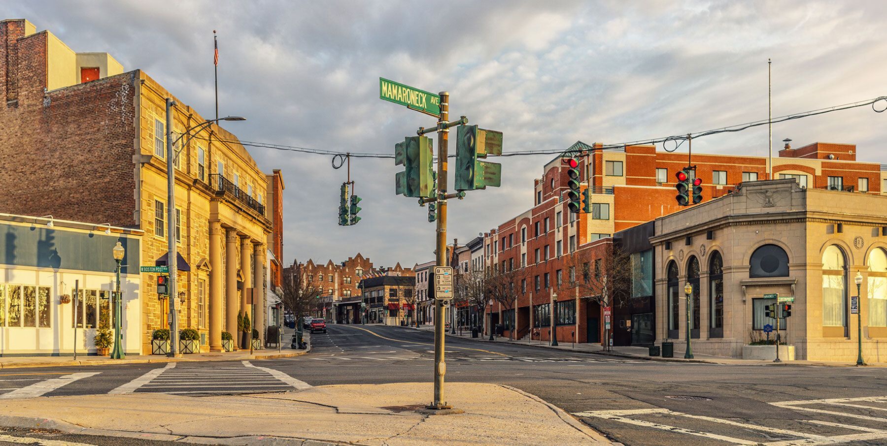 Quiet city street intersection with historic buildings and traffic lights at sunset