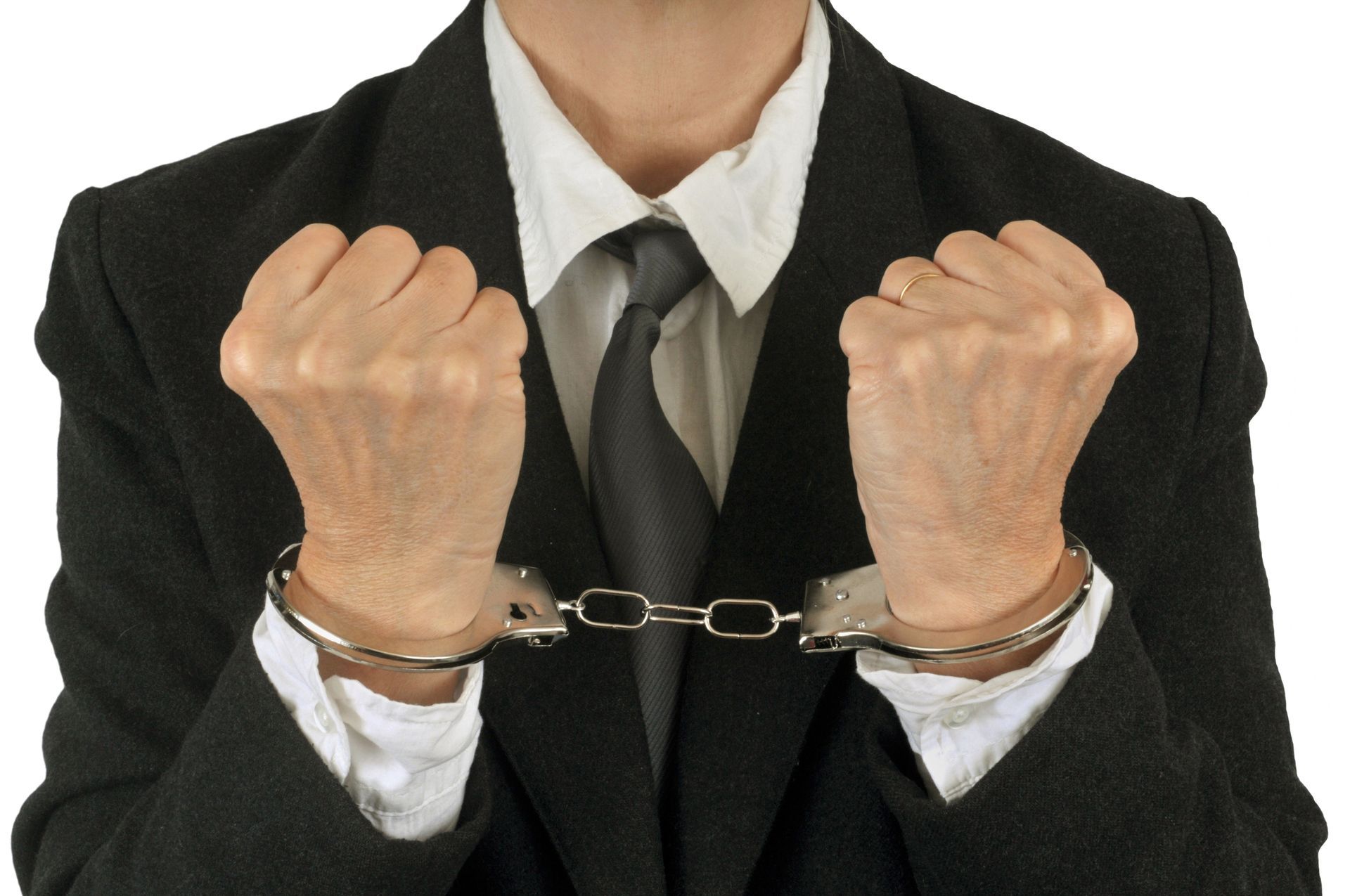 Person in a suit with handcuffs on wrists.